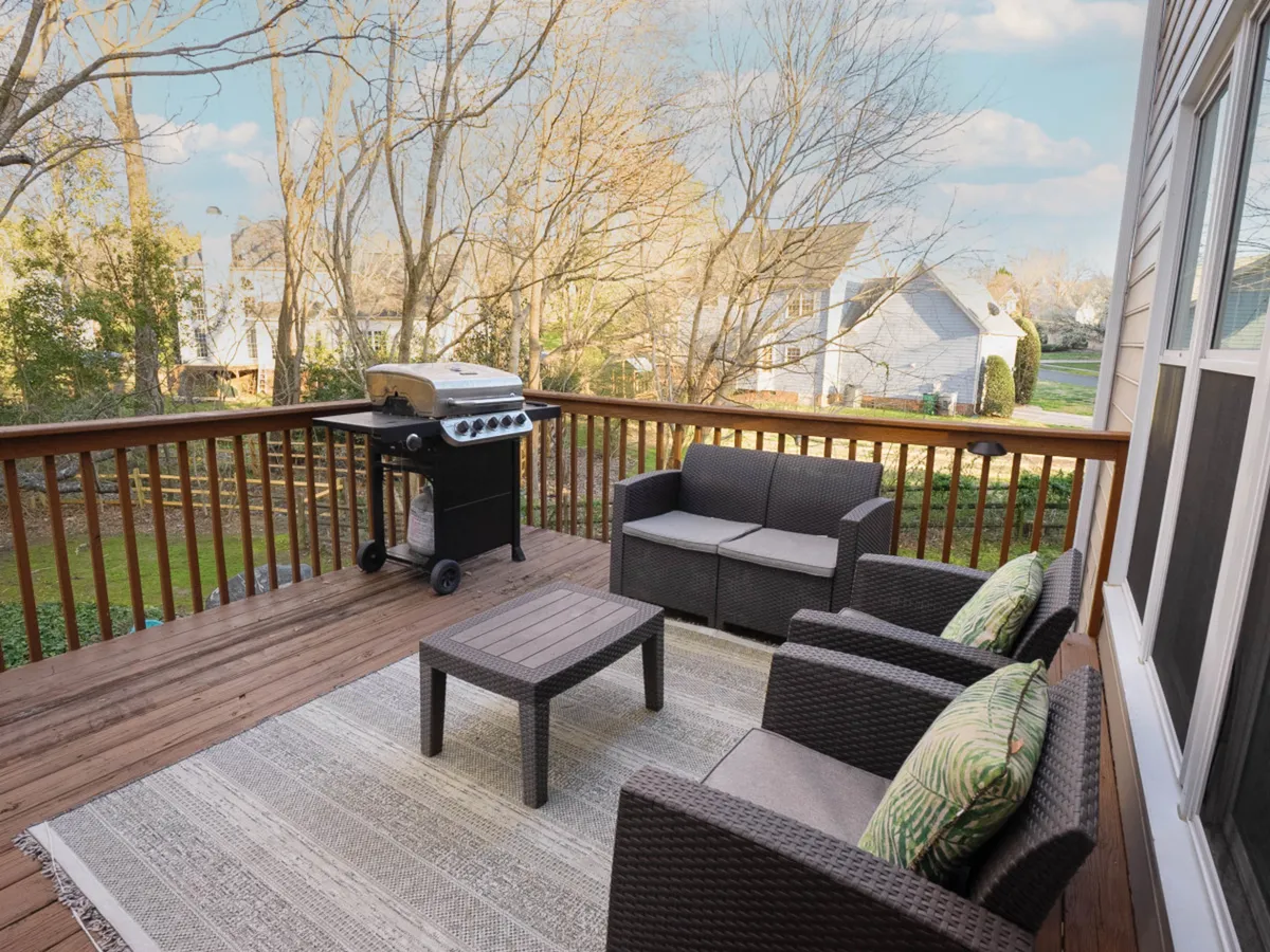This image depicts another angle of an outdoor seating area on a deck, featuring a modern grill and a welcoming rug. The space is styled for comfort and entertaining, inviting guests to linger outdoors.