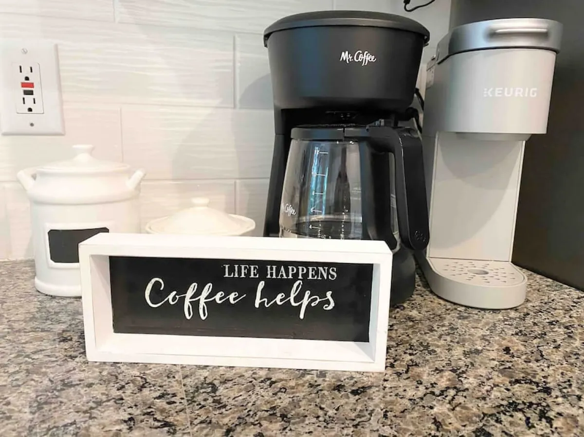 A cozy coffee station with both a Keurig and a Mr. Coffee machine, accompanied by a decorative sign. The setup suggests a welcoming environment where guests can easily prepare their favorite hot beverages.