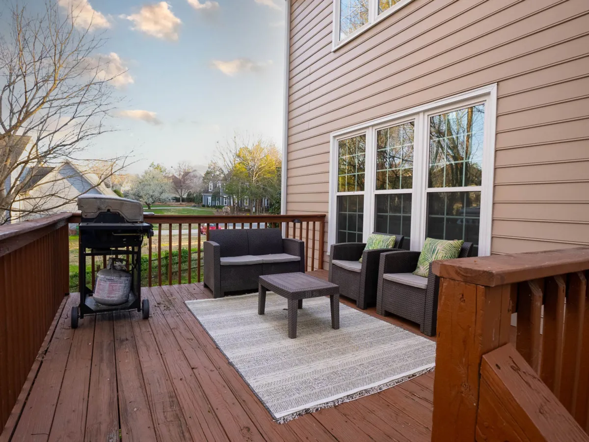 This image captures a spacious deck area with patio furniture and a grill set against the backdrop of the home. The scene is perfect for dining al fresco, enjoying morning coffee, or hosting group barbecues.