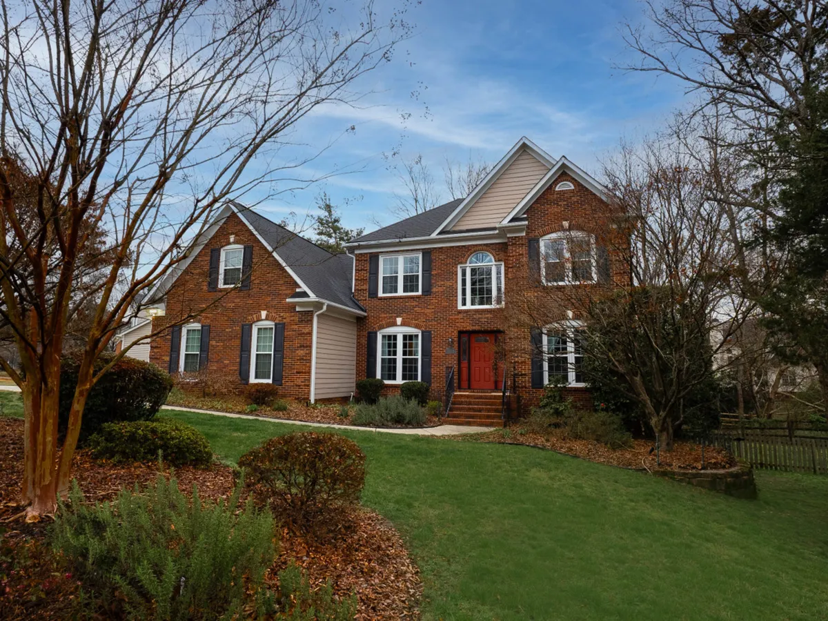 Featuring the home's elegant brick facade, charming front steps, red door, and landscaped garden, this exterior view immediately sets the scene for a welcoming and impressive arrival. It underscores the professionalism and comfort awaiting business travelers.